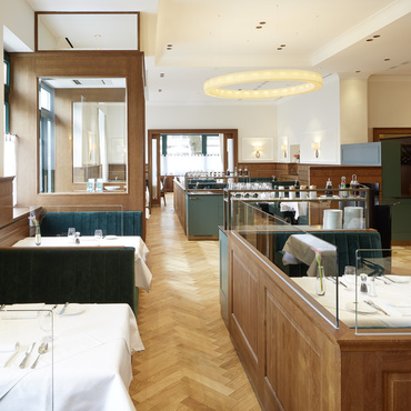 Eine schwarze Pfanne mit einem überbackenen Käseteller, garniert mit Kräutern, auf einem Holzbrett.